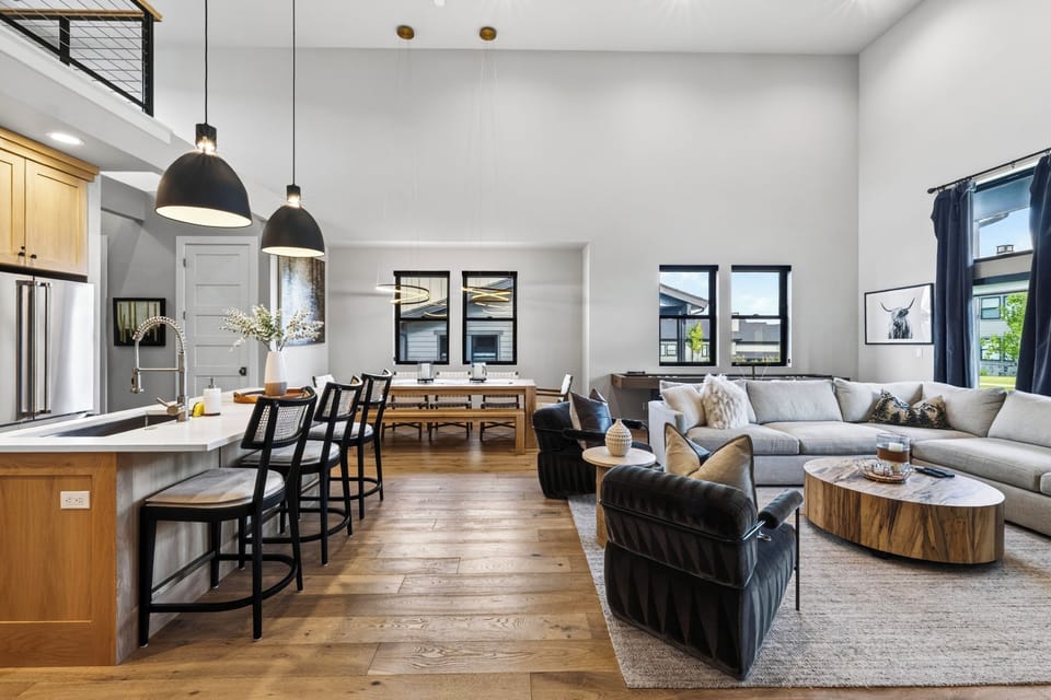Open-concept great room with vaulted ceilings, designer lounge seating, and a spacious kitchen made for gathering.