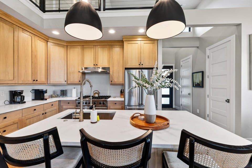 Chef’s kitchen with warm wood cabinetry, island seating, and an airy lofted layout.