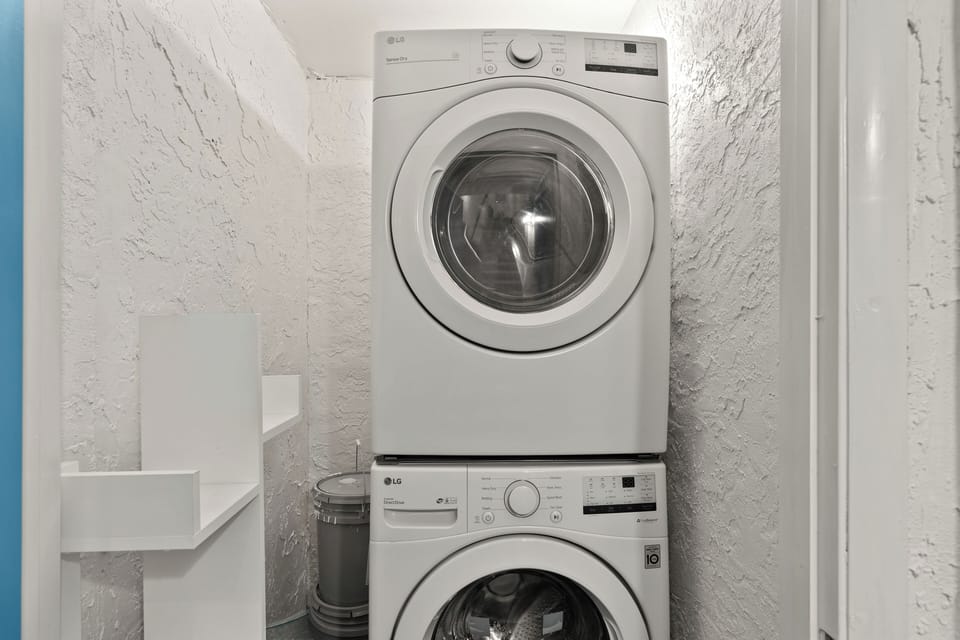 Convenient in-unit laundry nook equipped with a stacked full-size washer and dryer.