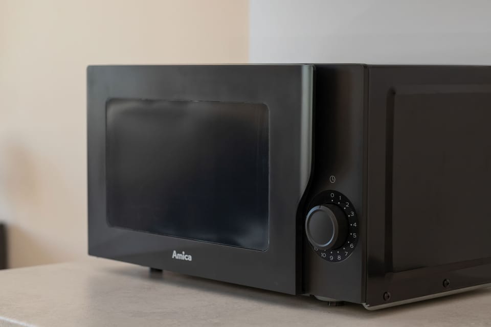 A close-up of a microwave placed on the kitchen countertop. The modern appliance is part of the apartment's fully equipped kitchenette.