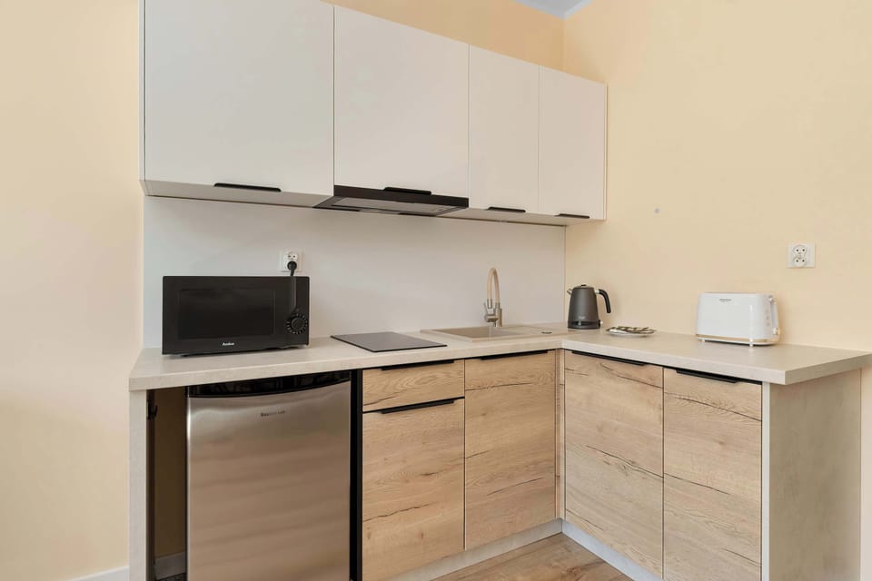 A modern kitchenette with white cabinets and wooden countertops. The space is compact and functional.