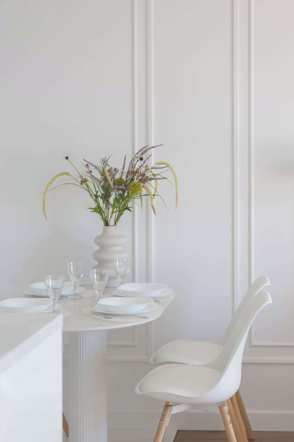 A close-up of a dining table with a clean, elegant setup and modern chairs. The minimalist design highlights a fresh and welcoming dining space.