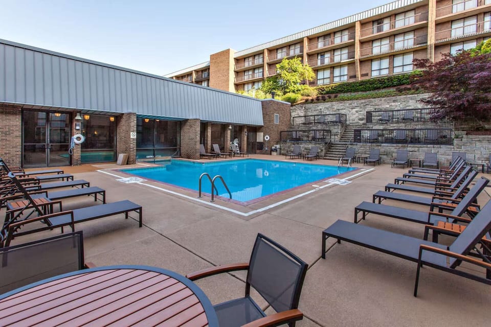 Outdoor pool deck with lounge chairs, tables, and tiered walls