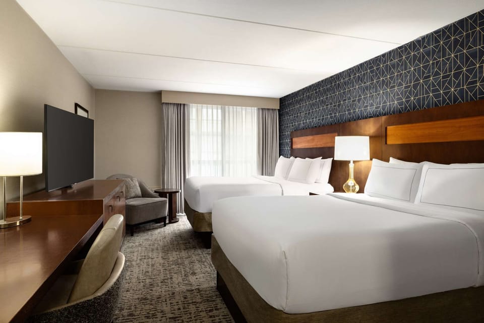 Double-bed guest room with TV, desk, chair, and patterned wall