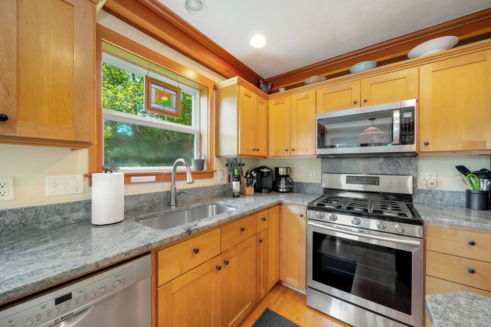 Fully equipped kitchen with gas stove, large fridge and drip pot and pod coffee maker.