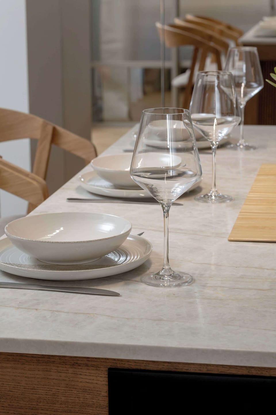 A close-up of the dining area highlights neatly arranged plates, glasses, and cutlery on a wooden table. The simple table setting adds a welcoming touch for shared meals.