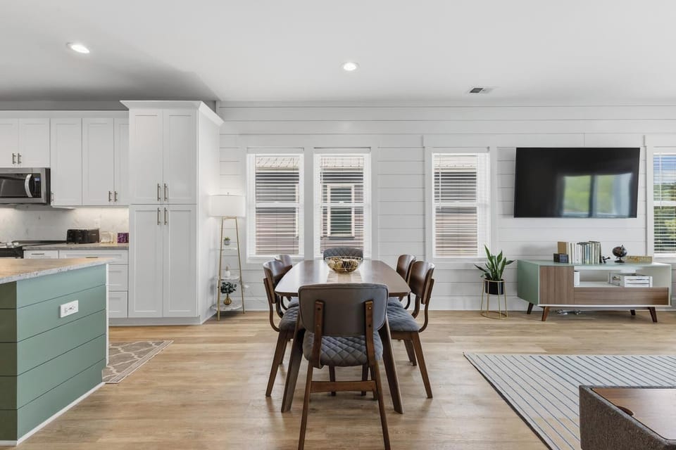 Gather around the elegant dining table with family, enjoying natural light from windows and the stylish, modern décor that flows through this open-concept living space.