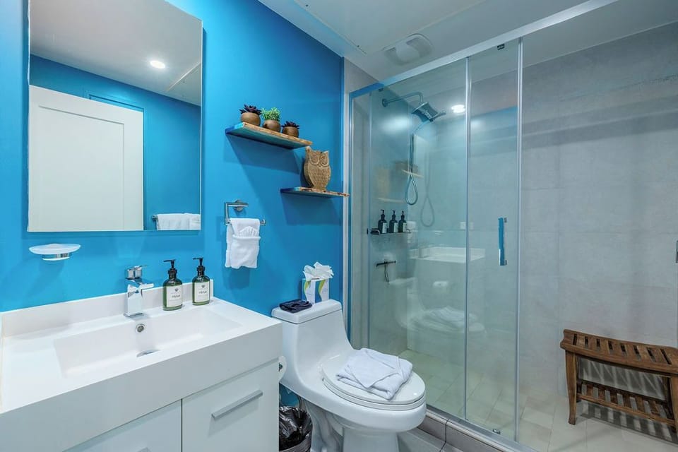Step into your modern bathroom where vibrant blue walls meet sleek fixtures. Luxurious amenities await, with a spacious glass-enclosed shower and thoughtful touches throughout your private retreat.