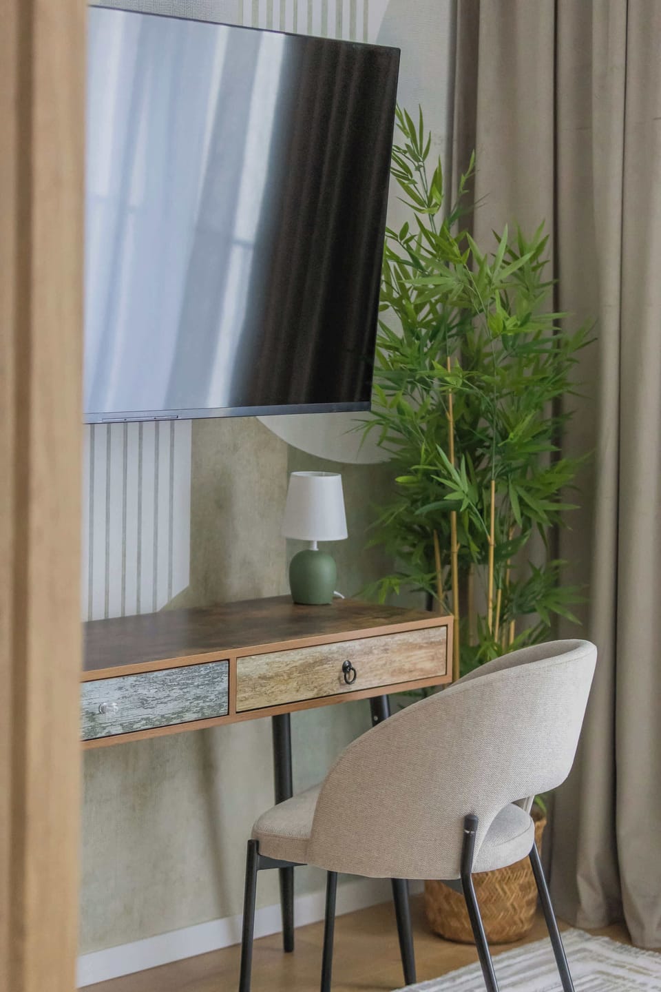 A close-up of a television mounted above a wooden shelf with decorative greenery nearby. Vertical wooden panels create a warm contemporary accent wall.