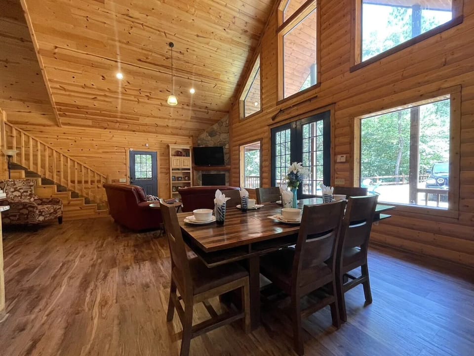 Sunlight pours through soaring windows in this open-concept space where you'll share meals at the handsome dining table and relax by the fireplace in cozy seating.