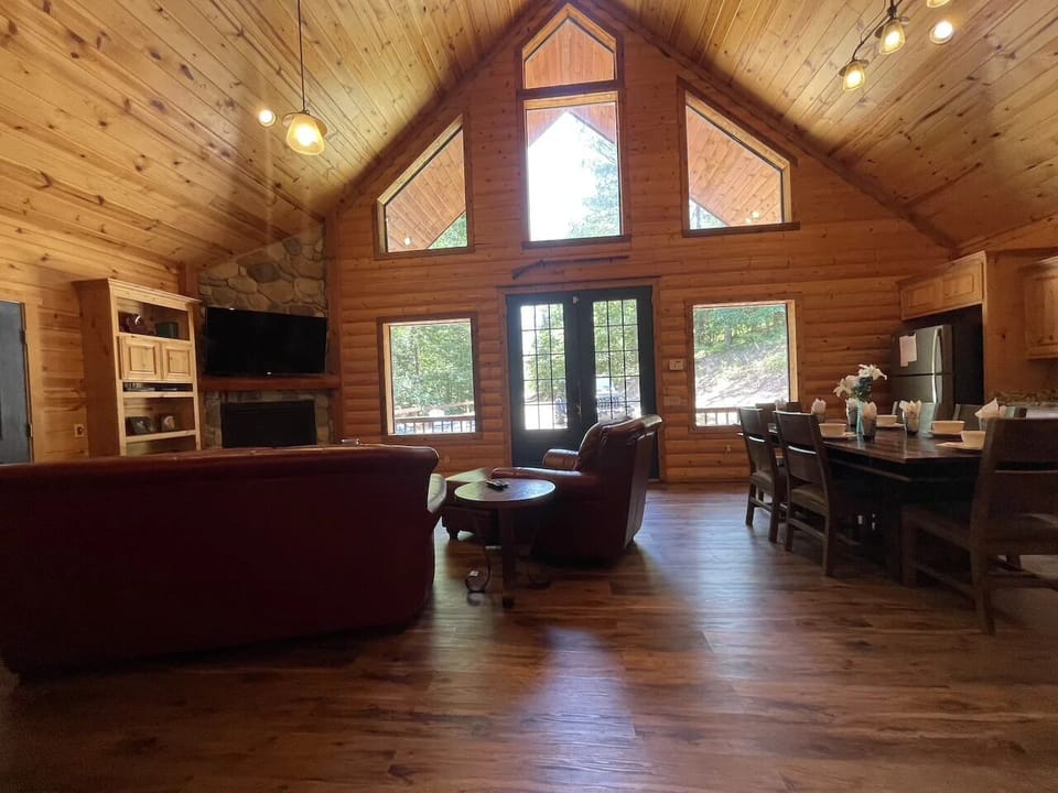 Step into your warm, wood-lined retreat with soaring cathedral ceilings and natural light streaming through expansive windows. Unwind by the cozy fireplace or gather around the inviting dining table for meals and memories.