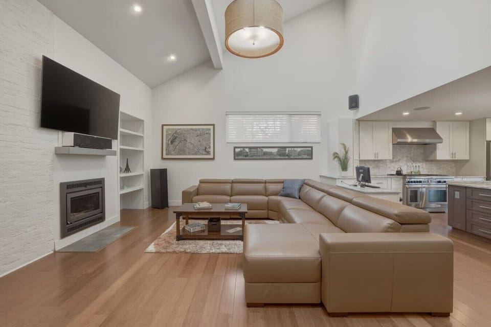 Spacious, upscale living space with soaring ceilings, smart TV, and fireplace
