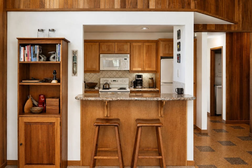 Your open kitchen welcomes you with warm wood tones, granite counters, and full appliances—perfect for brewing morning coffee or whipping up meals at the breakfast bar.
