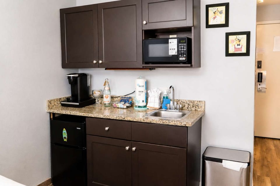 Compact kitchenette station equipped with a microwave, coffee maker, sink, and mini fridge