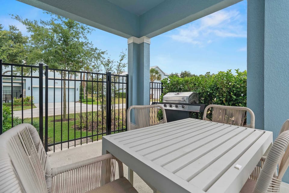 Covered patio with outdoor dining table and gas grill for relaxing meals.