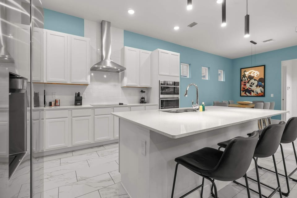Modern kitchen with white cabinetry, a large island, and blue accent walls.