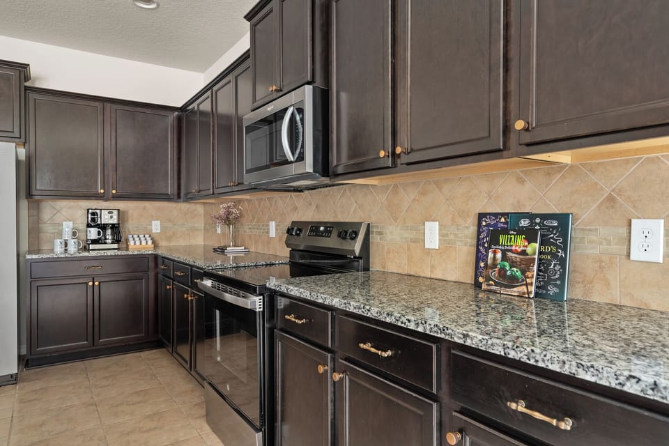 Kitchen with dark cabinets, stove, microwave, and villain-themed wall accents.