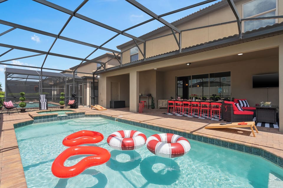 Pool deck with screened enclosure, lounge chairs, red villain-style floats
