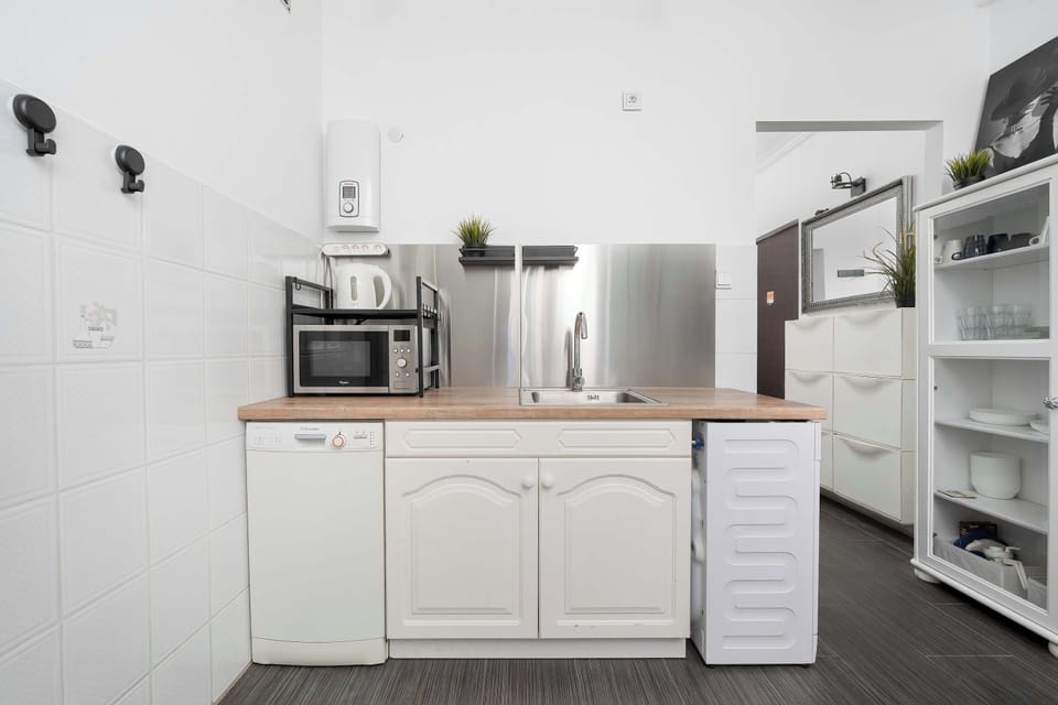 Compact modern kitchenette with white cabinetry, open shelving, and functional workspace.