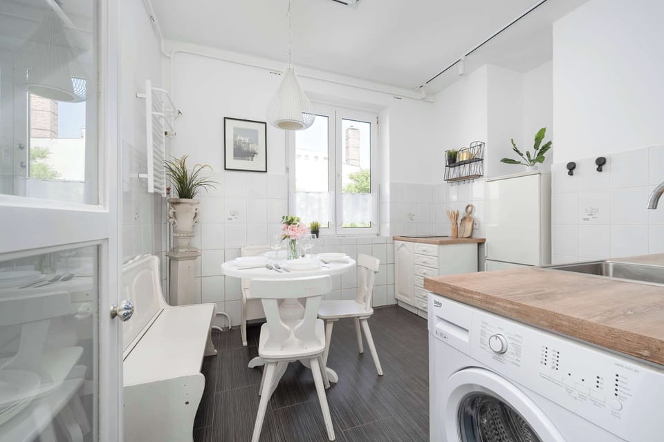 Bright kitchenette and dining area with white furniture and plenty of natural light.
