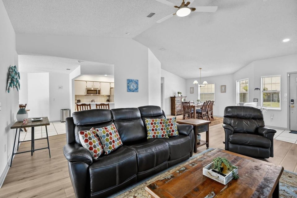 Cozy living space with plush seating and smart TV, perfect for family nights in, with views of the sunroom and pool.