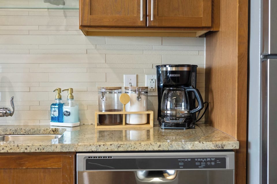 Well-stocked kitchen counter with coffee maker, wood cabinets, and granite countertops.