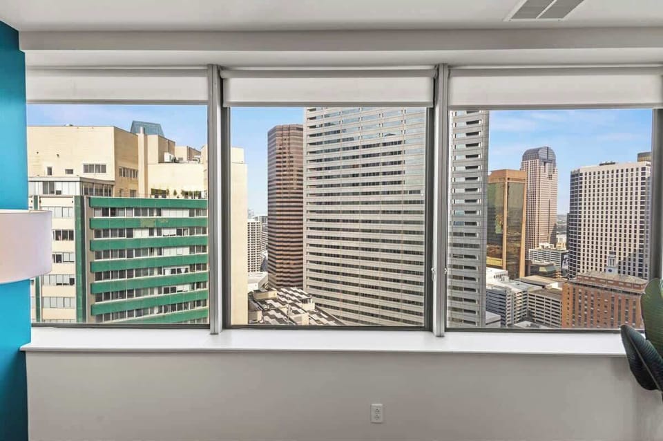 Lounge sky-high in a chic living room with expansive windows, offering panoramic city views. A vibrant, stylish space perfect for both relaxation and entertaining.