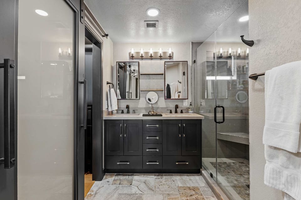 Refresh and unwind in the sleek primary en-suite bathroom, featuring a dual-sink vanity, glass walk-in shower, with a rainfall and handheld shower head.