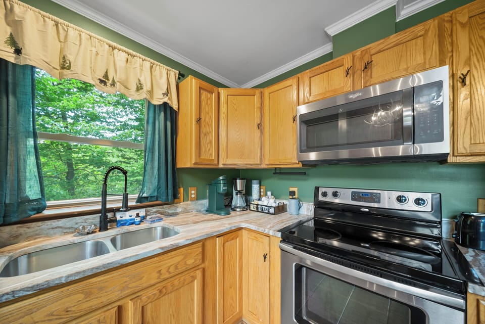 A fully equipped kitchen at The Mountain Hearth II, with treetop views and a cozy mountain vibe ready for big group meals.