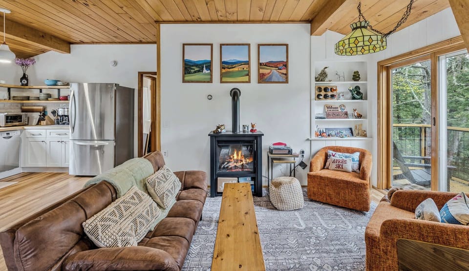 Living room with fireplace, leather sofa, and kitchen beyond