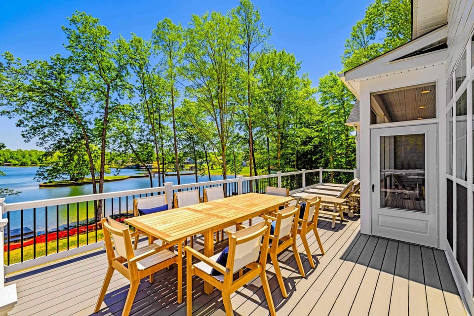 Deck - A long teak dining table set for eight stretches across the sun-soaked deck, with the lake glittering through the trees.