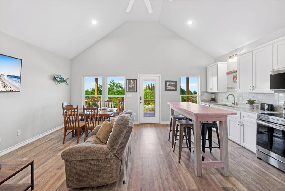 Bright open-concept living, dining, and kitchen space with vaulted ceilings and easy deck access.