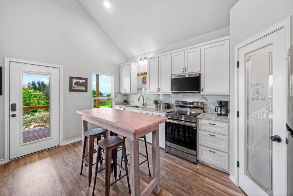 Bright kitchen with island seating, stainless appliances, and easy deck access for coastal meals in.