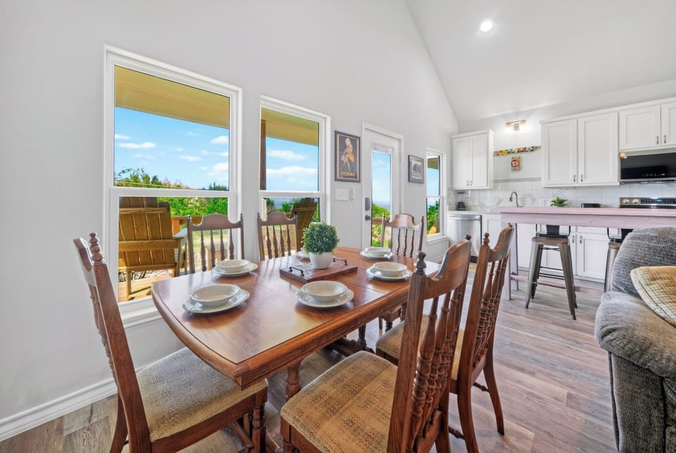Bright living and dining area with vaulted ceilings, cozy seating, and coastal-inspired decor.