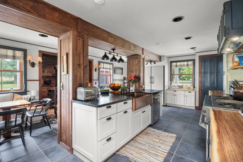 Airy kitchen view showcasing the blend of rustic exposed beams and modern white cabinetry.