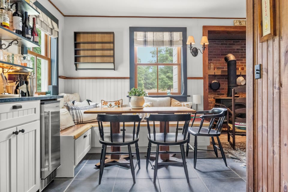 Charming breakfast nook with built-in bench seating and a rustic wood-burning stove nearby.
