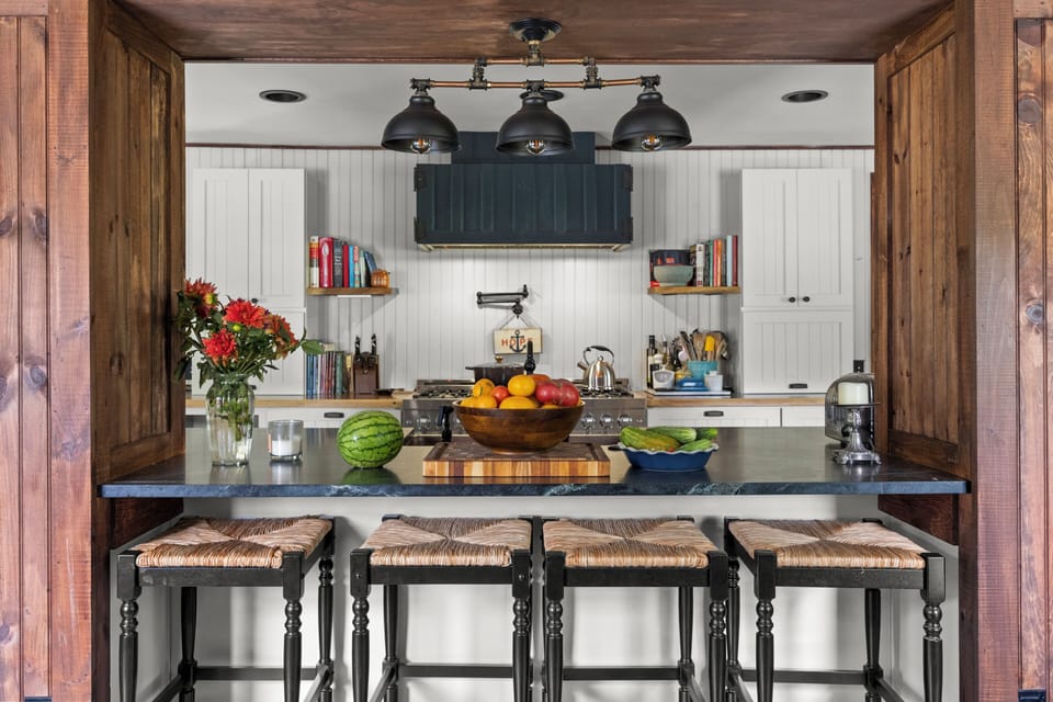Gourmet kitchen island with dark stone countertops, breakfast bar seating, and designer pendant lighting.