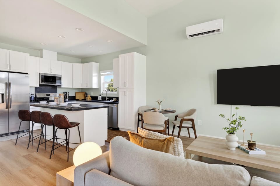Open-concept living and kitchen space with vaulted ceilings, island seating, and a bright modern coastal vibe.