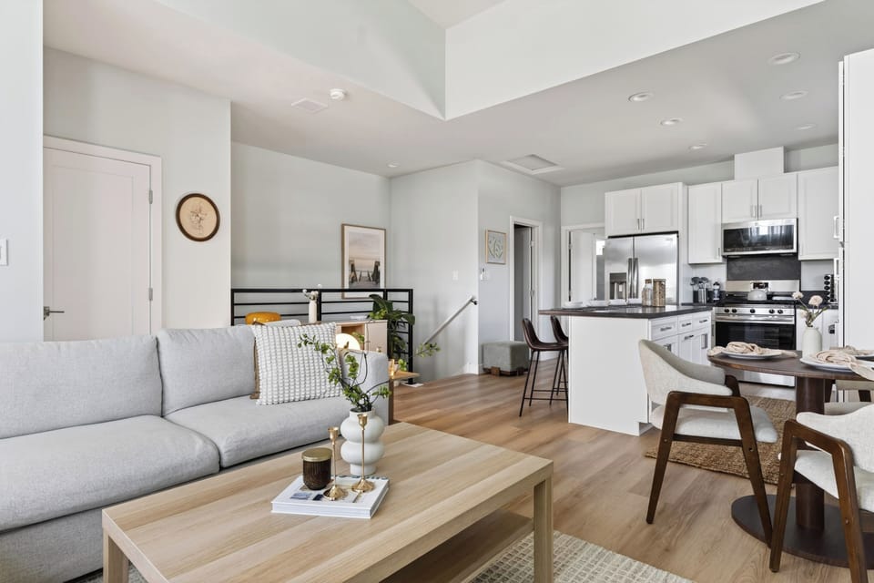 Open-concept living and kitchen space with vaulted ceilings, island seating, and a bright modern coastal vibe.