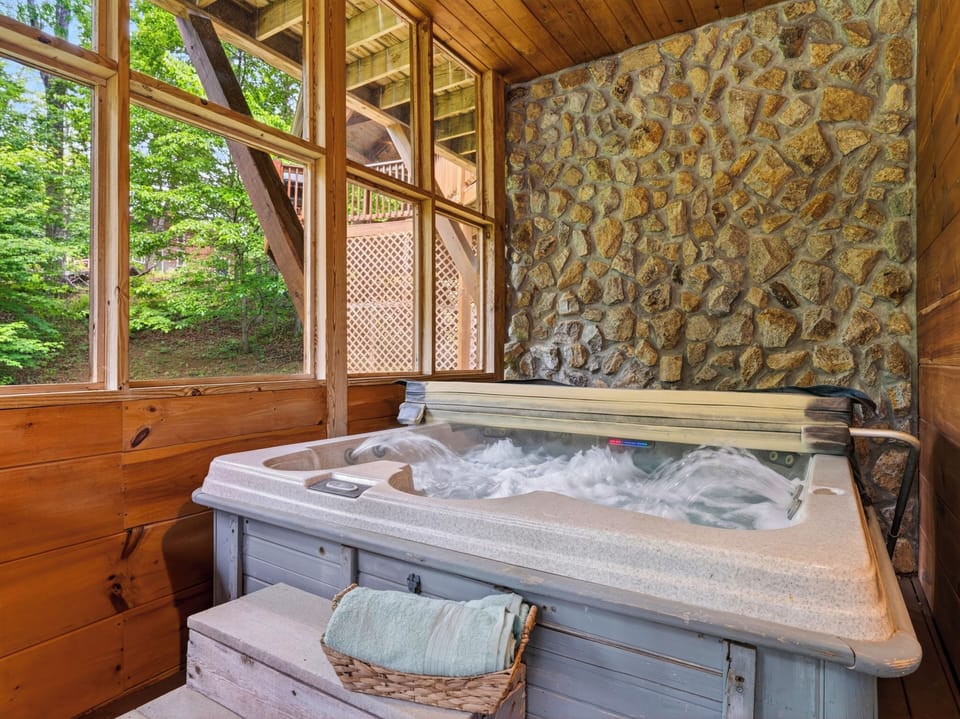 Private hot tub nook surrounded by rustic stone and forest views for the ultimate cabin unwind.