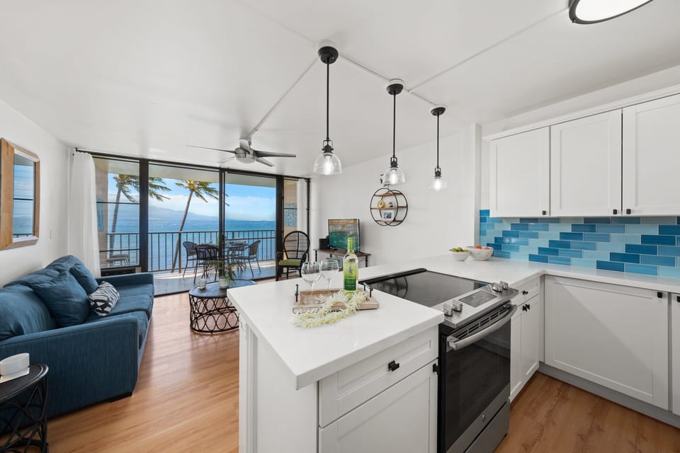 Modern kitchen with island seating and ocean views just beyond.