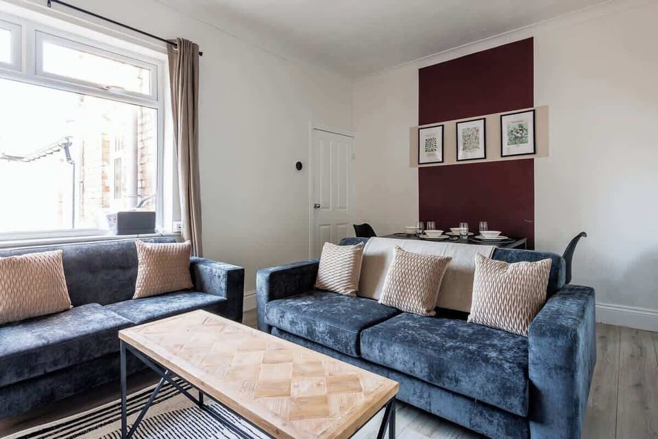 A comfortable living room with sofa seating, a coffee table, and soft furnishings arranged for relaxing indoors. The practical layout and subtle decorative touches create a welcoming space to unwind during your stay.