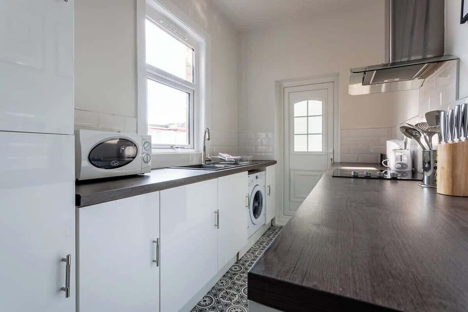 Modern cabinetry, a washing machine, and ample worktop space give this kitchen a practical and organized feel. The streamlined layout keeps everyday essentials within easy reach while supporting comfortable self-catering.