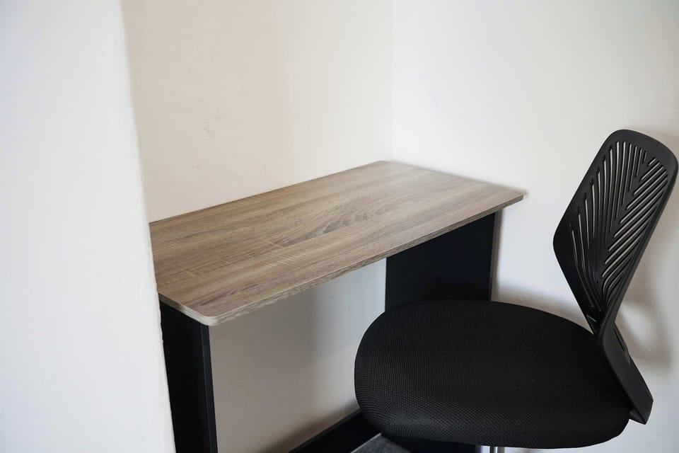A practical bedroom workspace with a desk and chair, offering a comfortable setup for catching up on work or planning your stay. The simple layout and neutral styling keep the room feeling calm, open, and easy to settle into.