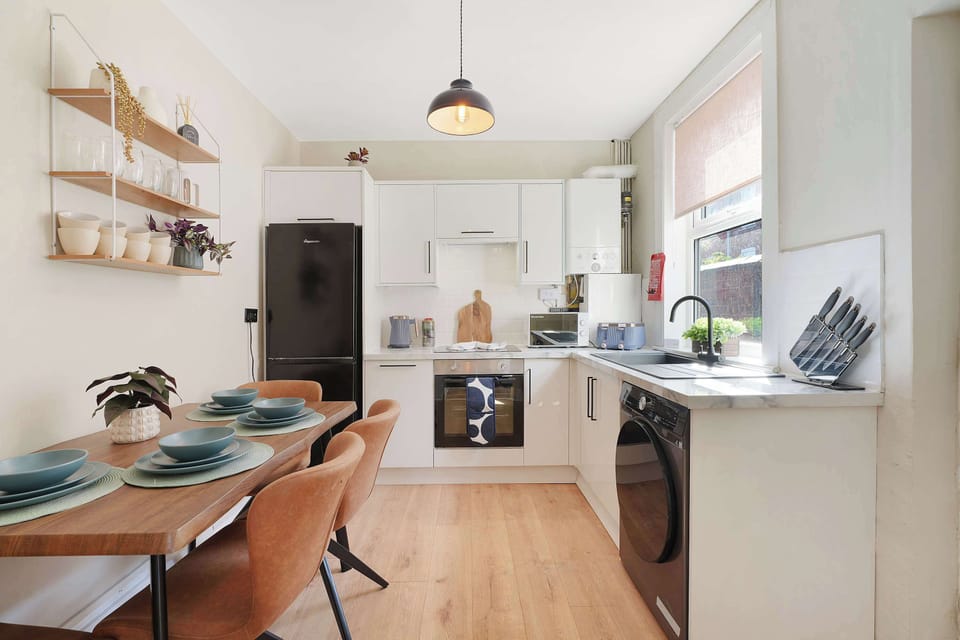 A well-equipped kitchen with integrated dining space, modern appliances, and generous worktop areas for everyday cooking. Open shelving, practical storage, and comfortable seating create an easy setup for shared meals during your stay.