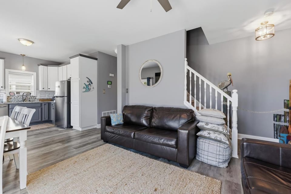 Relax in your spacious open-concept living area with modern coastal touches, where the kitchen flows seamlessly into the comfortable lounge—perfect for gathering after beach adventures.