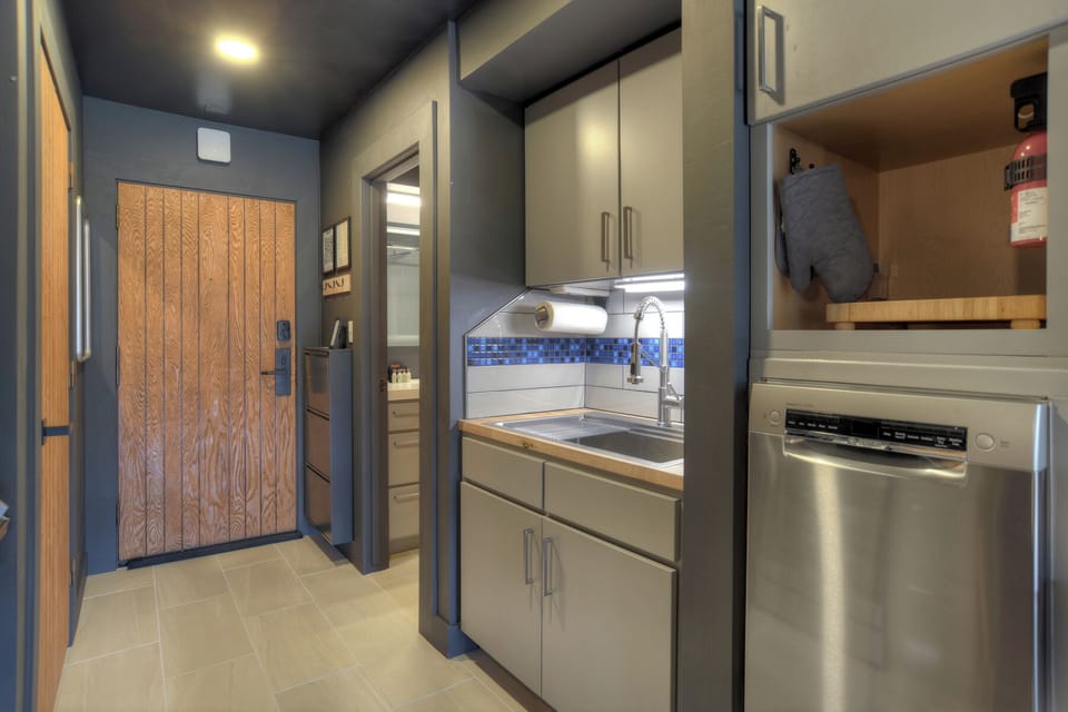Small kitchen area with full-sized fridge, stove, oven and dish washer.