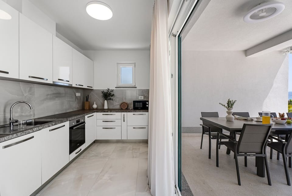 The fully stocked kitchen is equipped with modern appliances, including a microwave, coffee capsule machine, and all the essentials for a seamless stay