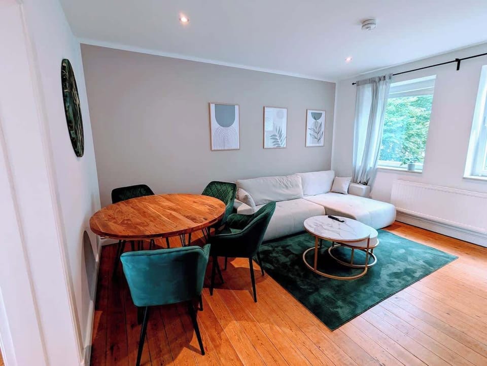 Der Essbereich mit rundem Holztisch und das Ecksofa im Wohnzimmer.