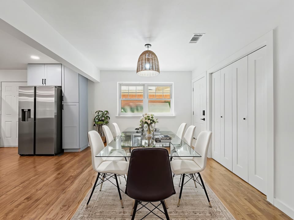 Gather around this elegant glass dining table where meals become memorable. Modern white kitchen and abundant storage create your perfect culinary haven.